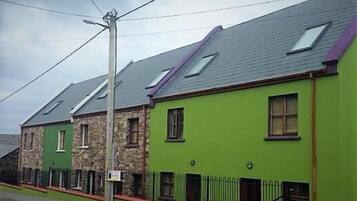 A row of terraced houses with a green facade and stone detailing.