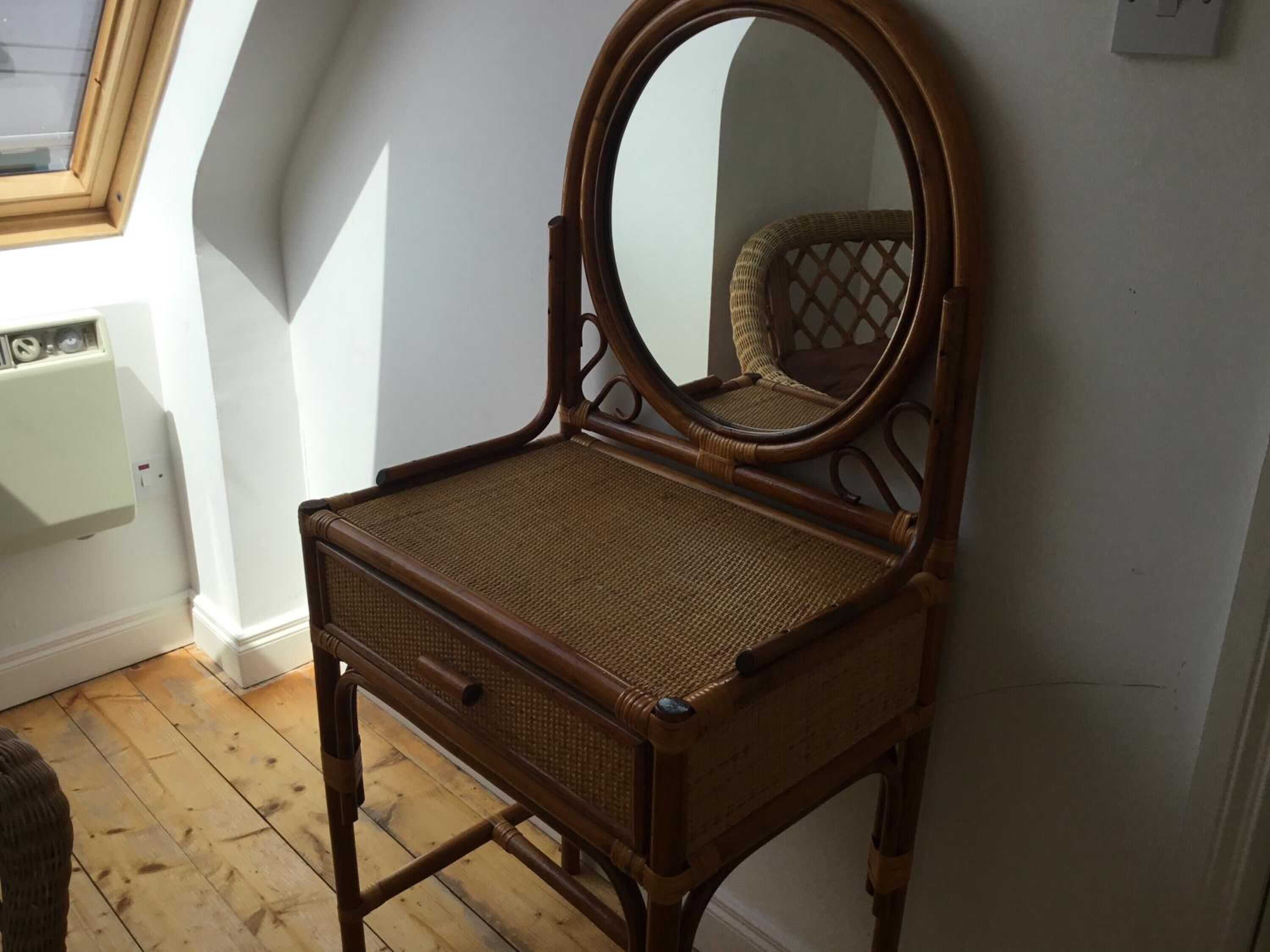 Une coiffeuse en bois avec un miroir, placée près d’une fenêtre donnant sur le ciel.