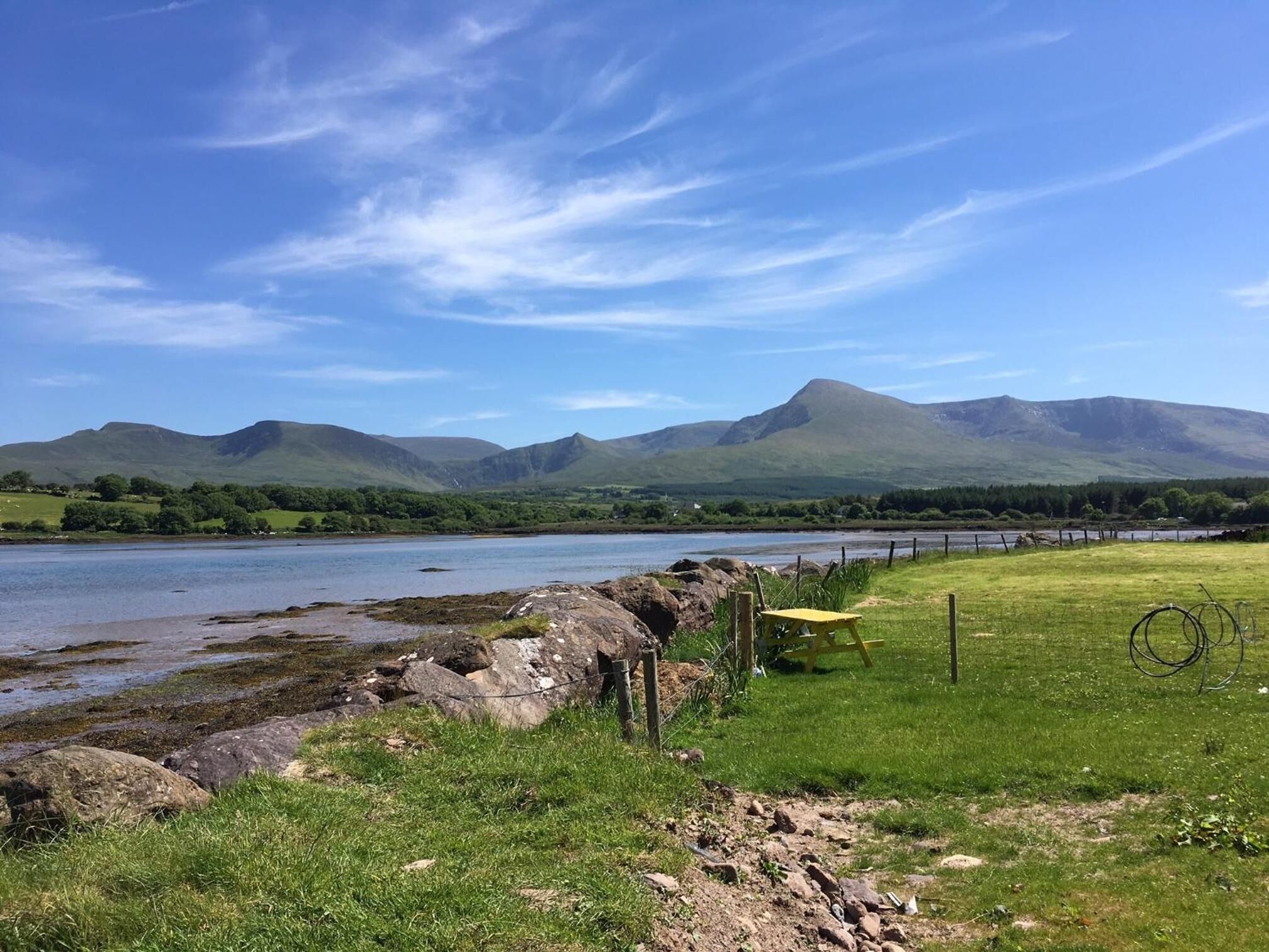 A scenic landscape with a river, grassy fields, and mountains in the background.
