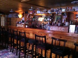 A bar area with wooden bar counter and stools.