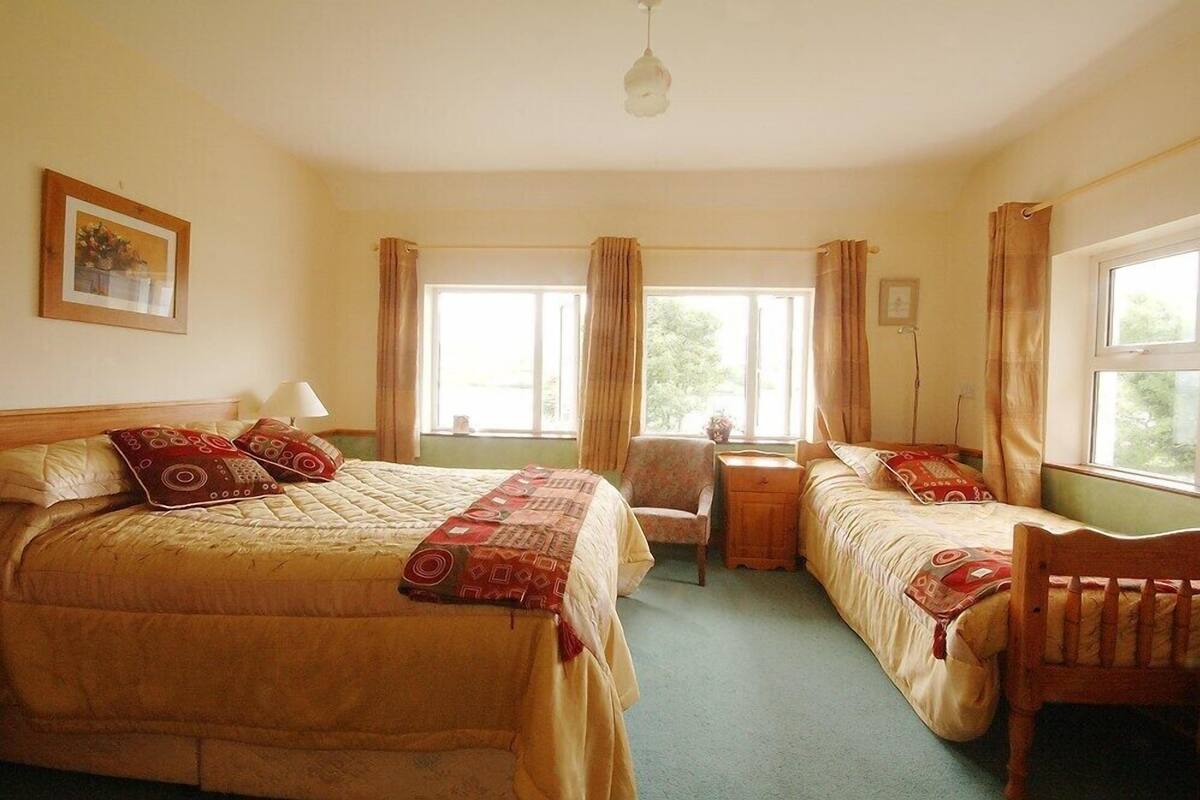 A room with two beds, a chair, a desk, and a lamp.