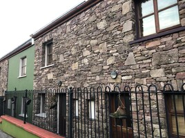 A stone building with a green facade and a black metal fence.