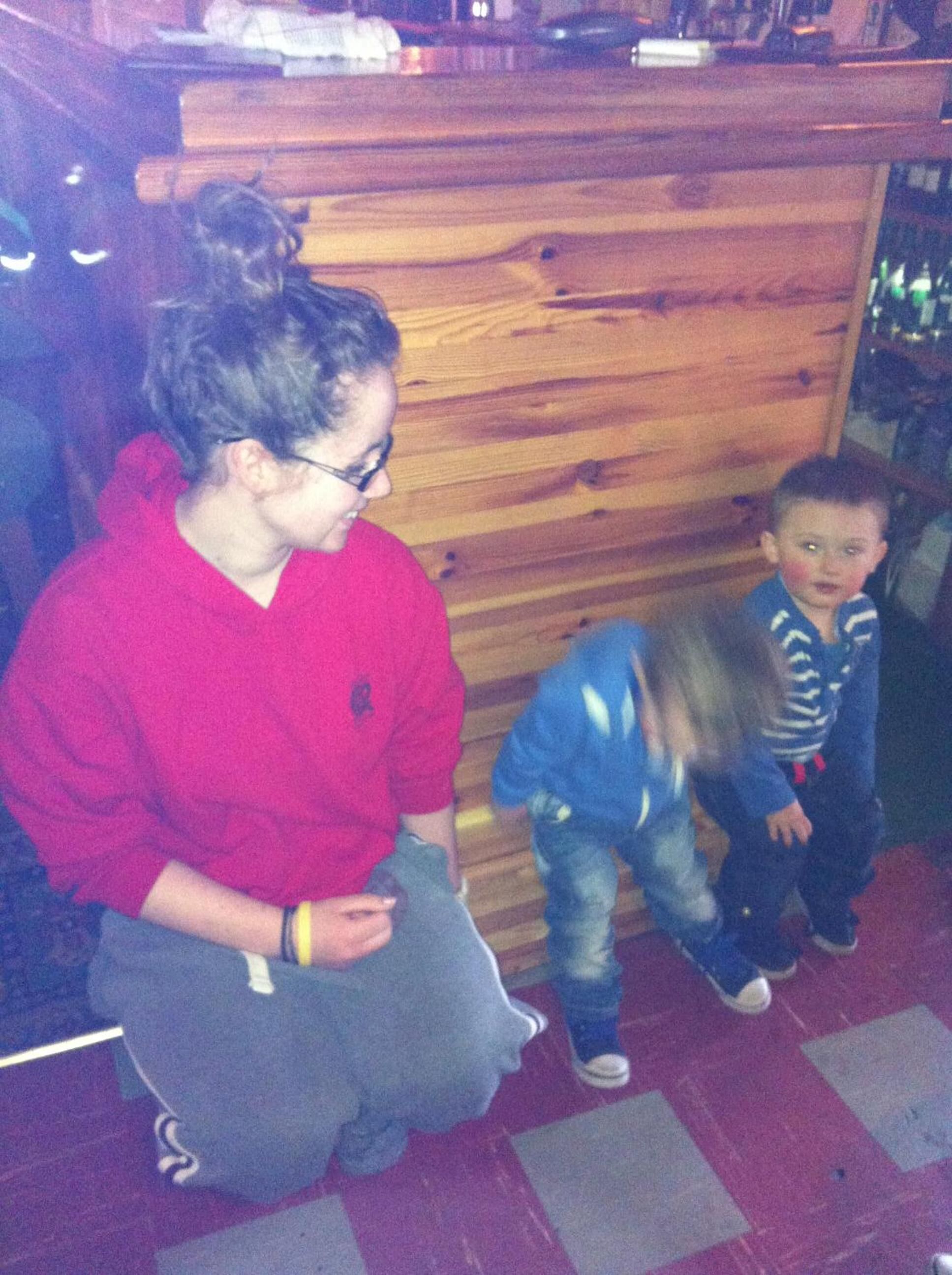 A wooden interior with a person in a red shirt and a child in a blue jacket.