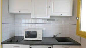 A compact kitchen with white cabinets, a microwave, a sink, and a dishwasher. - Cozy studio for 4 with terrace in Saint-Lary-Soulan (Saint-Lary-Soulan)