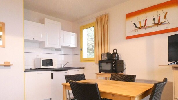 A compact kitchen with white cabinets, a microwave, and a dining table with four chairs. - Cozy studio for 4 with terrace in Saint-Lary-Soulan (Saint-Lary-Soulan)