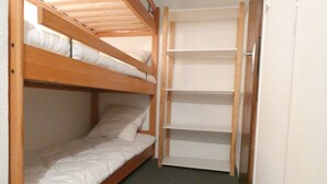 A bunk bed with a wooden frame and white bedding, a built-in shelf unit, and a carpeted floor. - Cozy studio for 4 with terrace in Saint-Lary-Soulan (Saint-Lary-Soulan)