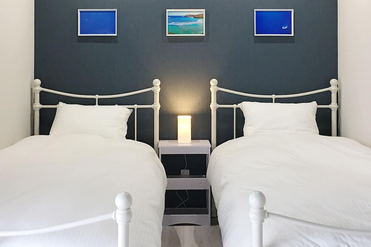 A double room with two single beds, a bedside table with a lamp, and three framed pictures on the wall.