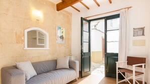 A room with a sofa, a chair, a door, and a wall-mounted light fixture. - Roques 24, 3 bedroom house, Ciutadella (Ciutadella de Menorca)