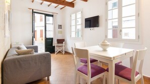 A cozy living area with a sofa, a dining table with chairs, and a TV mounted on the wall. - Roques 24, 3 bedroom house, Ciutadella (Ciutadella de Menorca)