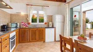 Una cocina con gabinetes de madera, un microondas, un tostador, un lavabo y un refrigerador.