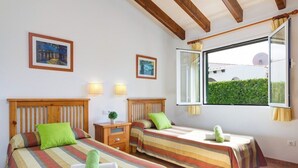 Una habitación con dos camas, una ventana con vistas y una mesita de noche con lámpara.