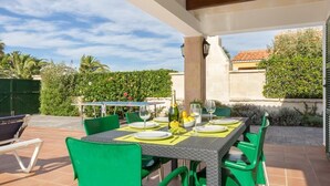 Un patio al aire libre con una mesa lista para cenar, sillas verdes y una botella de champán.