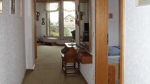 A narrow hallway with a wooden bench, a mirror, and a window leading to a balcony. - 3 room apartment 80sqm - Apartments Eggert (Neustadt in Holstein)