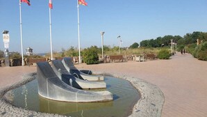A water feature with benches and flags in a park setting. - 3 room apartment 80sqm - Apartments Eggert (Neustadt in Holstein)