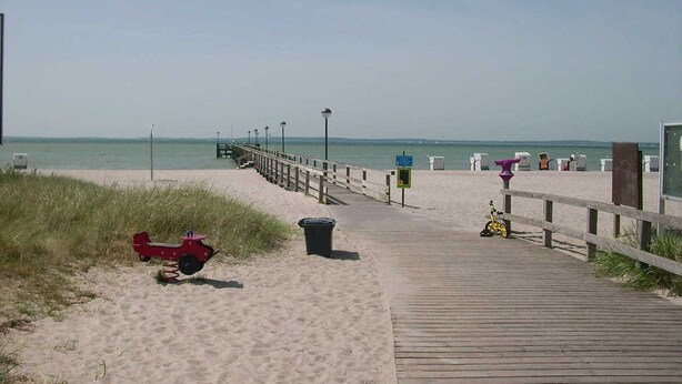 A wooden boardwalk leading to a beach with a clear view of the ocean. - 3 room apartment 80sqm - Apartments Eggert (Neustadt in Holstein)