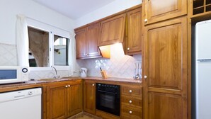A kitchen with wooden cabinets, a dishwasher, an oven, and a window.