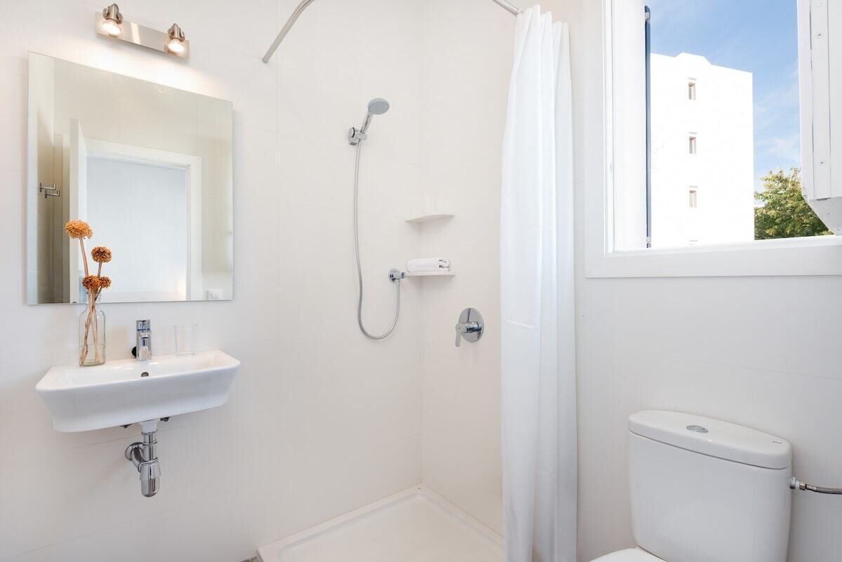 Kylpyhuone, jossa on valkoinen pesuallas, peili, suihku ja wc.