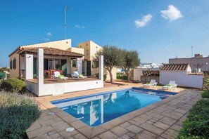 Une maison moderne dotée d’une piscine, d’un espace salon extérieur et d’un jardin.