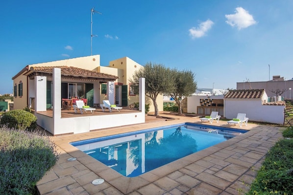 A modern house with a swimming pool, outdoor seating, and a garden.