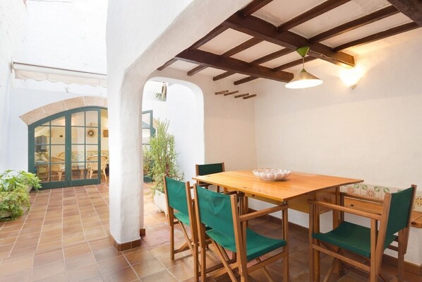 A dining area with a wooden table and chairs, a bowl on the table, and a ceiling with exposed beams.