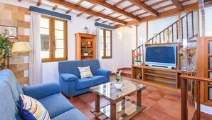 A spacious living area with a blue sofa, a glass coffee table, and a TV on a wooden stand. - Sa Font 45, 4 bedroom house, Ciutadella (Ciutadella de Menorca)