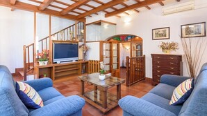A spacious living room with a wooden ceiling, a television, a glass coffee table, and blue sofas. - Sa Font 45, 4 bedroom house, Ciutadella (Ciutadella de Menorca)