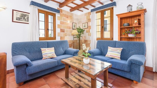 A cozy living room with two blue sofas, a glass coffee table, and a wooden cabinet with decorative items. - Sa Font 45, 4 bedroom house, Ciutadella (Ciutadella de Menorca)