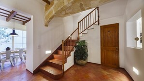 A staircase with wooden steps and a metal railing, leading to a door. There is a potted plant beside the stairs and a window with natural light. - Sant Isidre 50, 4 bedroom house, Ciutadella (Ciutadella de Menorca)