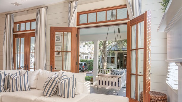 A cozy room with a white sofa, striped pillows, and a wooden swing chair. - Updated Wilson Village 4 Bedroom Cottage  Amenity access available (Bluffton)