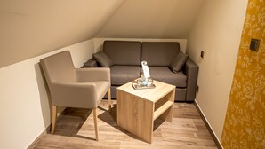 Et lille, hyggeligt rum med en sofa, en lænestol og et træsofabord.
