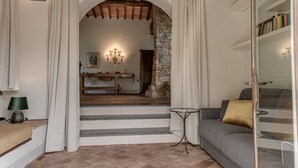 A living room with a grey sofa, a small round table, and a staircase leading to another room.