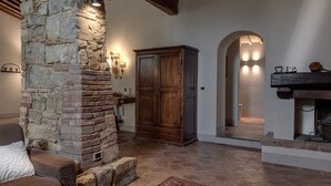 A stone fireplace, wooden cabinet, and arched doorway in a rustic interior.