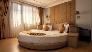 Un dormitorio moderno con una cama curvada, un cabecero capitonado y una mesita de noche con una lámpara.