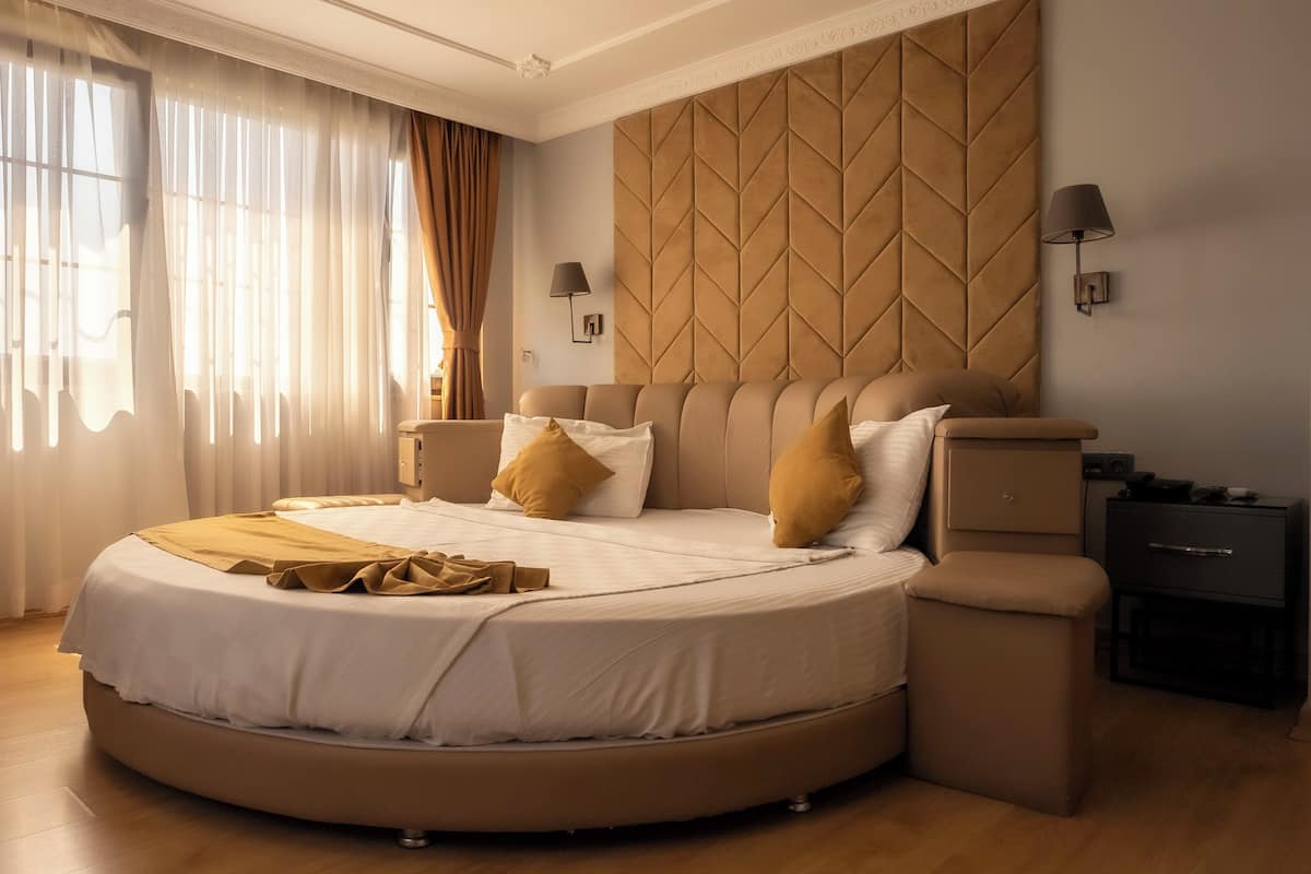 A modern bedroom with a curved bed, a tufted headboard, and a nightstand with a lamp.