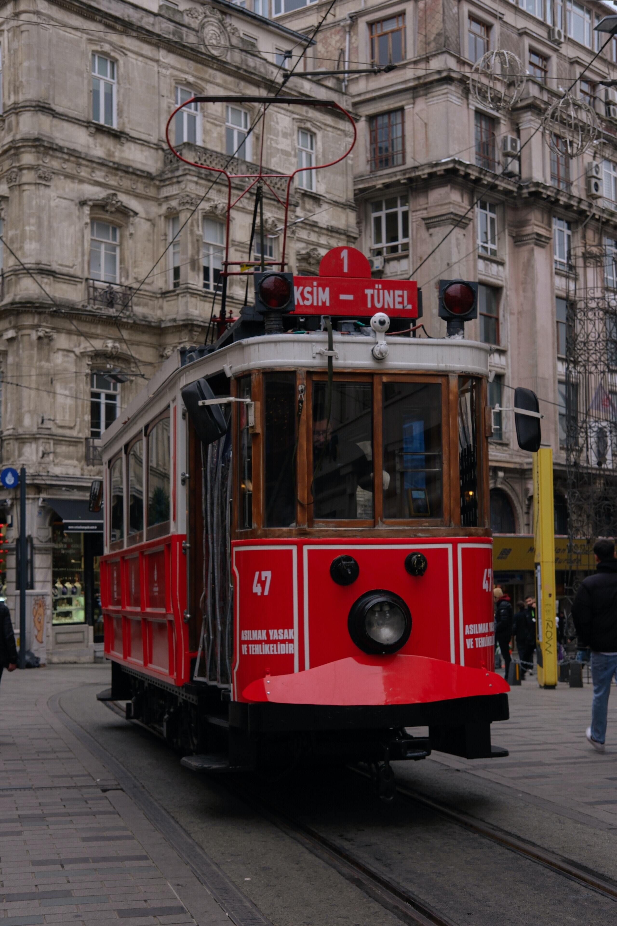 A red tram with a sign reading "KSIM - TUNEL" on a city street.