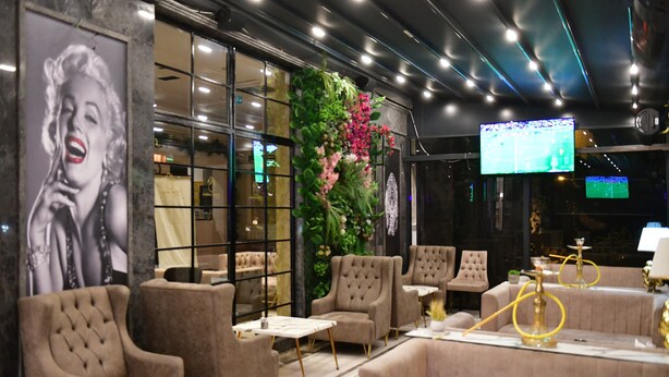 Un área de estar moderna con asientos cómodos, una gran pantalla de televisión y una pared decorativa con plantas.