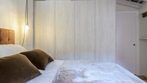 Quarto com cama, travesseiros, luminária e porta branca.