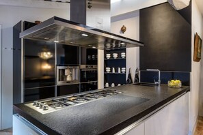 A modern kitchen with a built-in gas stove, stainless steel appliances, and a black countertop.
