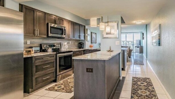 A modern kitchen with dark wood cabinets, stainless steel appliances, and a central island.