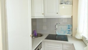 A compact kitchen with white cabinetry, a stainless steel sink, and a microwave. - Becker House Alice 36 (Sylt)