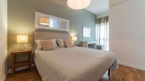A bedroom with a large bed, bedside lamps, a desk, and a mirror. - GuestHost - This comfortable 60 m2 apartment is located on the seventh and top floor (with a lift, which however is not suitable for the disabled) of a period building.The house is perfect for 4 peopleIt is located a few steps from Castel Sant'Angelo, cr (Roma)