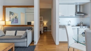 A compact living space with a sofa, a glass dining table, a kitchen area with cabinets and a stove, and a hallway leading to a bedroom. - GuestHost - This comfortable 60 m2 apartment is located on the seventh and top floor (with a lift, which however is not suitable for the disabled) of a period building.The house is perfect for 4 peopleIt is located a few steps from Castel Sant'Angelo, cr (Roma)