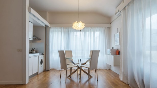 A modern kitchen with a washing machine, a dining table with chairs, and a hanging light fixture. - GuestHost - This comfortable 60 m2 apartment is located on the seventh and top floor (with a lift, which however is not suitable for the disabled) of a period building.The house is perfect for 4 peopleIt is located a few steps from Castel Sant'Angelo, cr (Roma)