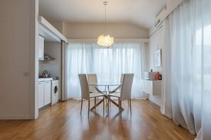 Una cocina moderna con lavadora, una mesa de comedor con sillas y una lámpara colgante.