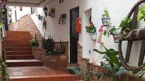 A narrow outdoor corridor with a tiled floor, a small garden area with plants, and a staircase leading to an upper level. - Charming apartment in the center of Malaga (Málaga)