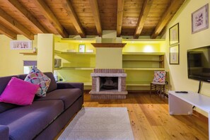 A cozy living room with a fireplace, a sofa, a TV, and a bookshelf.