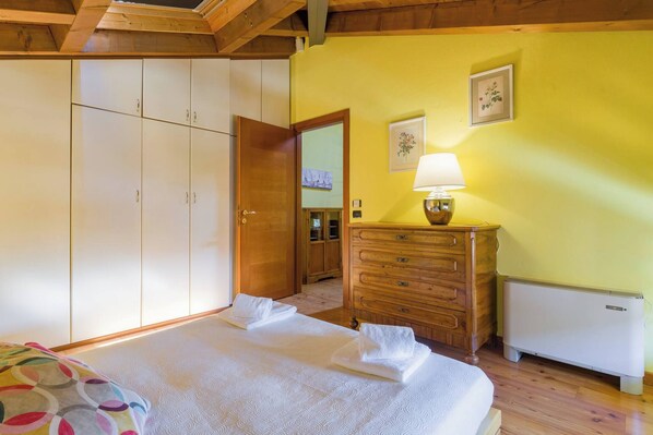 A bedroom with a bed, a dresser, a radiator, and a door leading to another room.