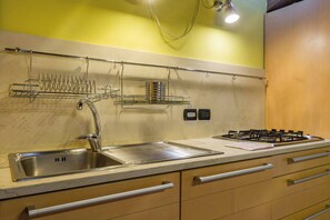 A kitchen with a stainless steel sink, a gas stove, and a dish rack.