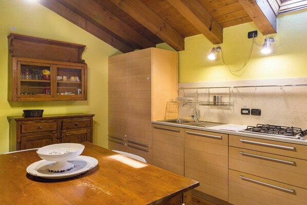 A kitchen with wooden cabinets, a sink, a stove, and a dining table with a bowl and plates.