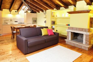 A cozy living room with a sofa, a fireplace, and a dining area with a table and chairs.